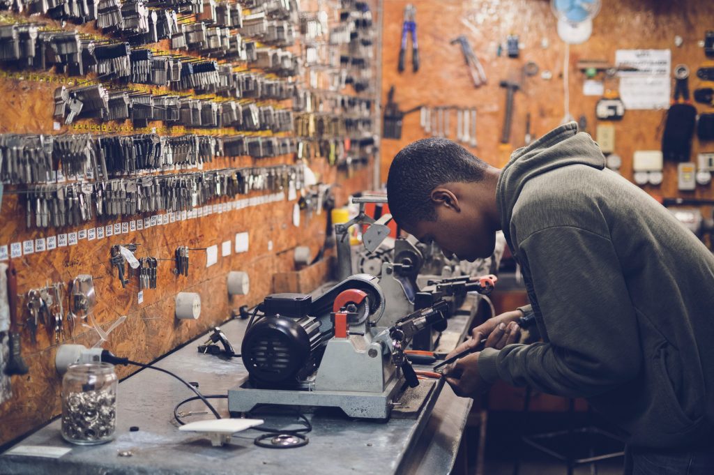 Ein Schwarzer junger Schlüsselmacher arbeitet an einer Schlüsselmaschine in seiner Werkstatt