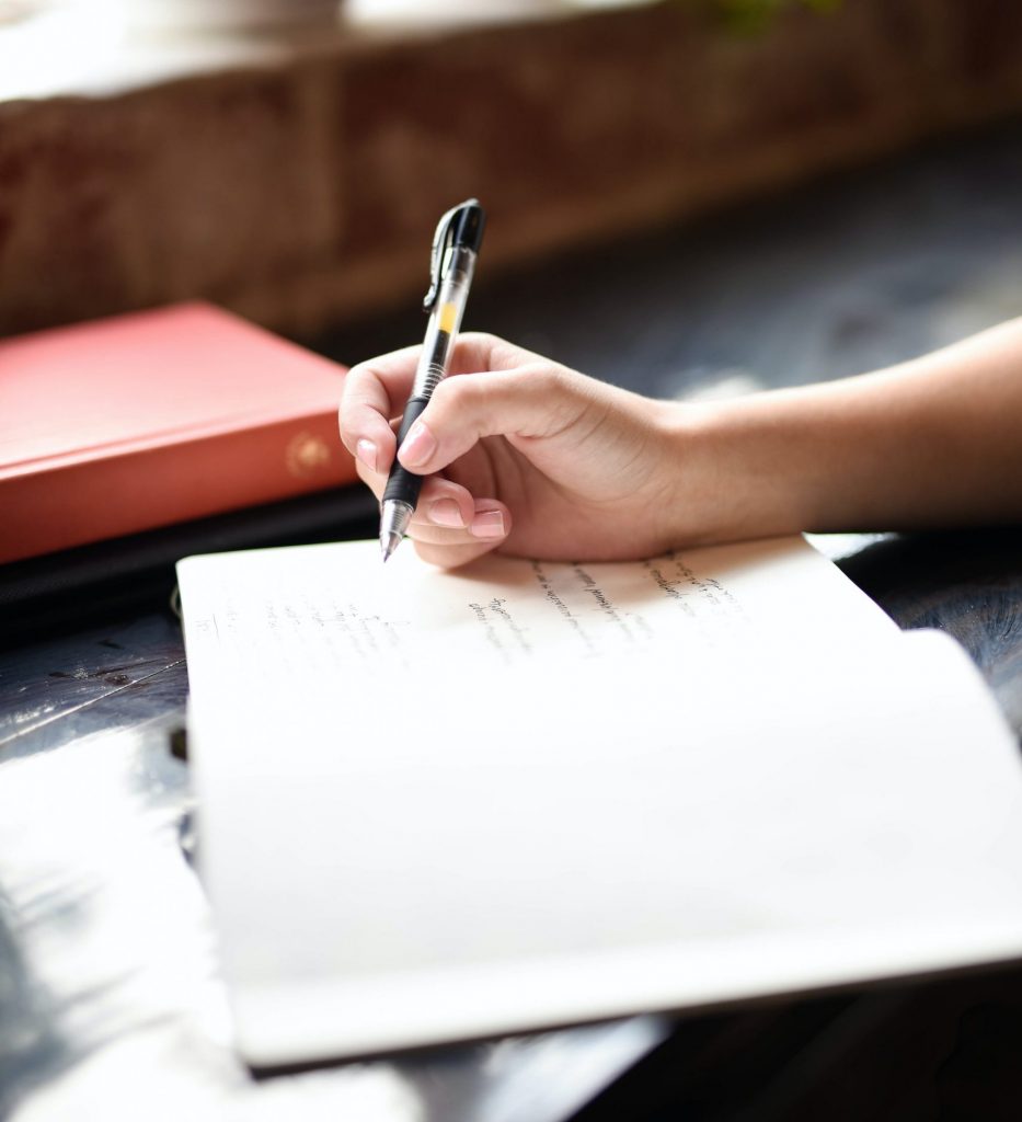 Hand mit Stift und Notizbuch beim Schreiben